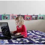 Toddler typing laptop in bed